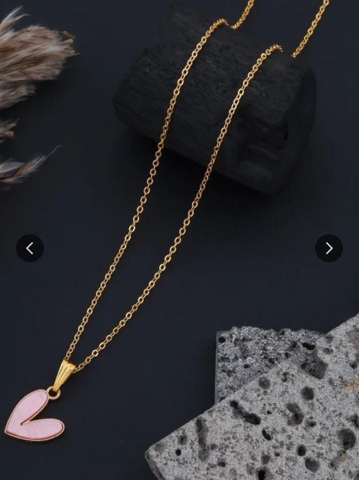 Pink love heart pendant necklace on gold chain against dark background