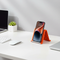 Orange foldable silicone stand holding a smartphone on a desk